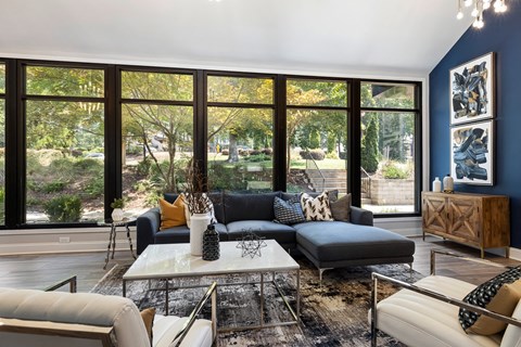 a living room with blue walls and large windows and a blue couch and coffee table